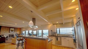 A spacious kitchen with a large island, wooden ceiling beams, and a view of the ocean. - Spectacular Ocean Front Views "Sea Star Escape" A (Brookings)
