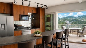 A modern kitchen with a bar area, a dining set, and a balcony with a view. - Updated 1BR/1BA - "Hillside Getaway" (Lovenlund)