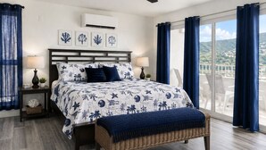 A bedroom with a bed, bedside tables, a ceiling fan, and a view through a large window. - Updated 1BR/1BA - "Hillside Getaway" (Lovenlund)