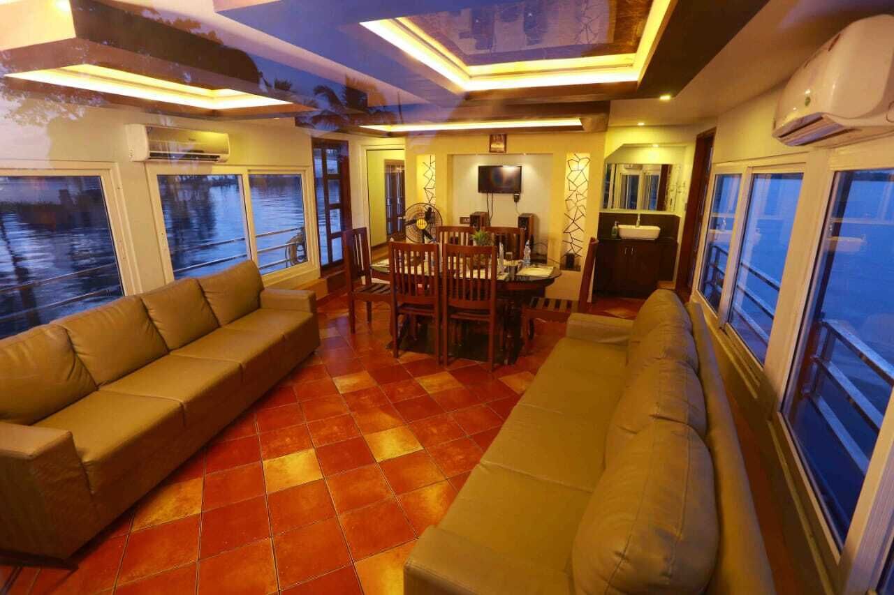 A cozy interior with a sofa, dining table, and chairs, large windows, and an air conditioning unit.