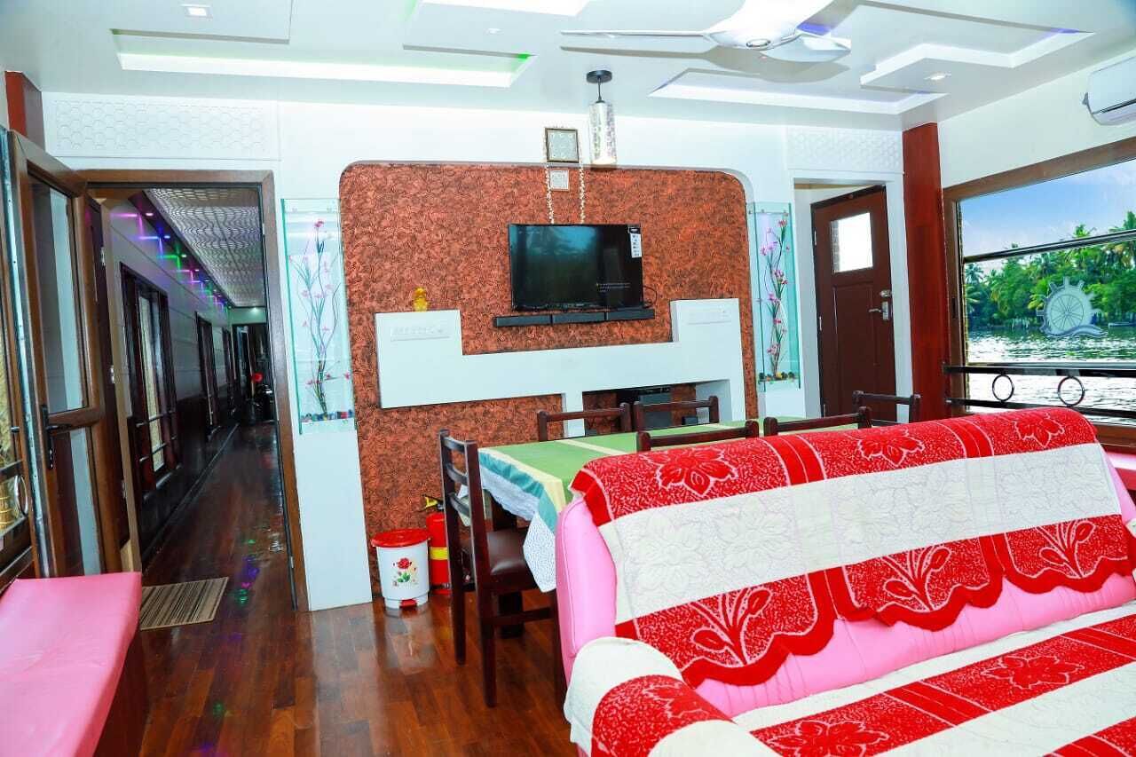 Una habitación con una televisión montada en una pared estampada, una mesa de comedor con sillas y un sofá con funda roja y blanca.