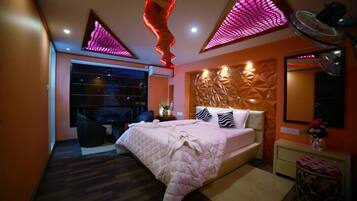 Relax in this stylish bedroom with a central bed, geometric wall panels, and a unique ceiling light fixture.
