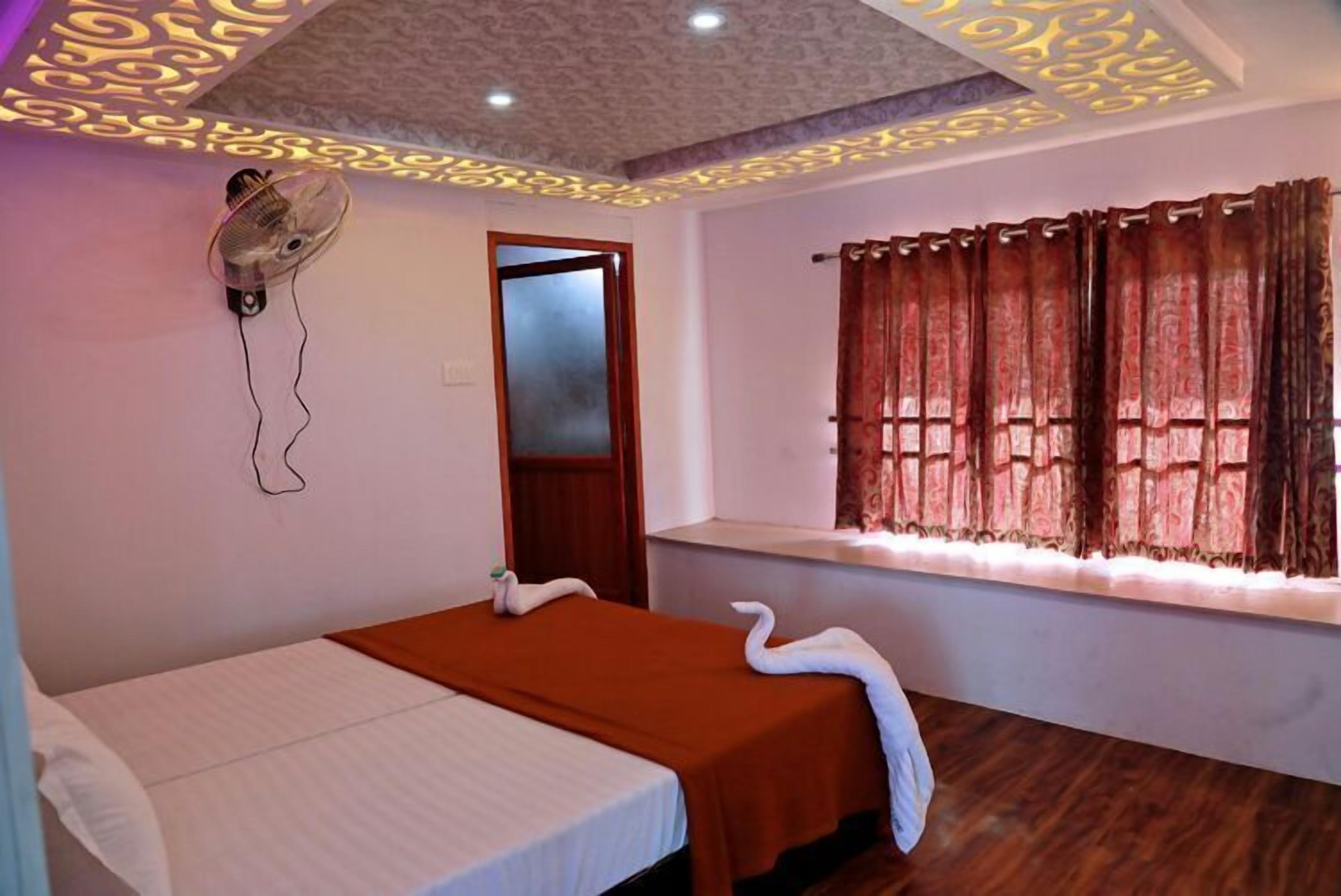 A room with a bed, a window with curtains, a ceiling fan, and a door.