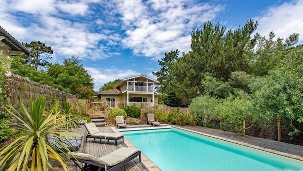 A backyard with a swimming pool, wooden deck, lounge chairs, and a house with a balcony. - Villa des Sables pool, 100M from the beach (Lège-Cap-Ferret)