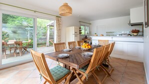 A dining area with a wooden table and chairs, a fruit bowl, and a hanging light fixture. - Villa des Sables pool, 100M from the beach (Lège-Cap-Ferret)