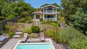 A two-story house with a pool, surrounded by a wooden deck and a wooden fence. - Villa des Sables pool, 100M from the beach (Lège-Cap-Ferret)