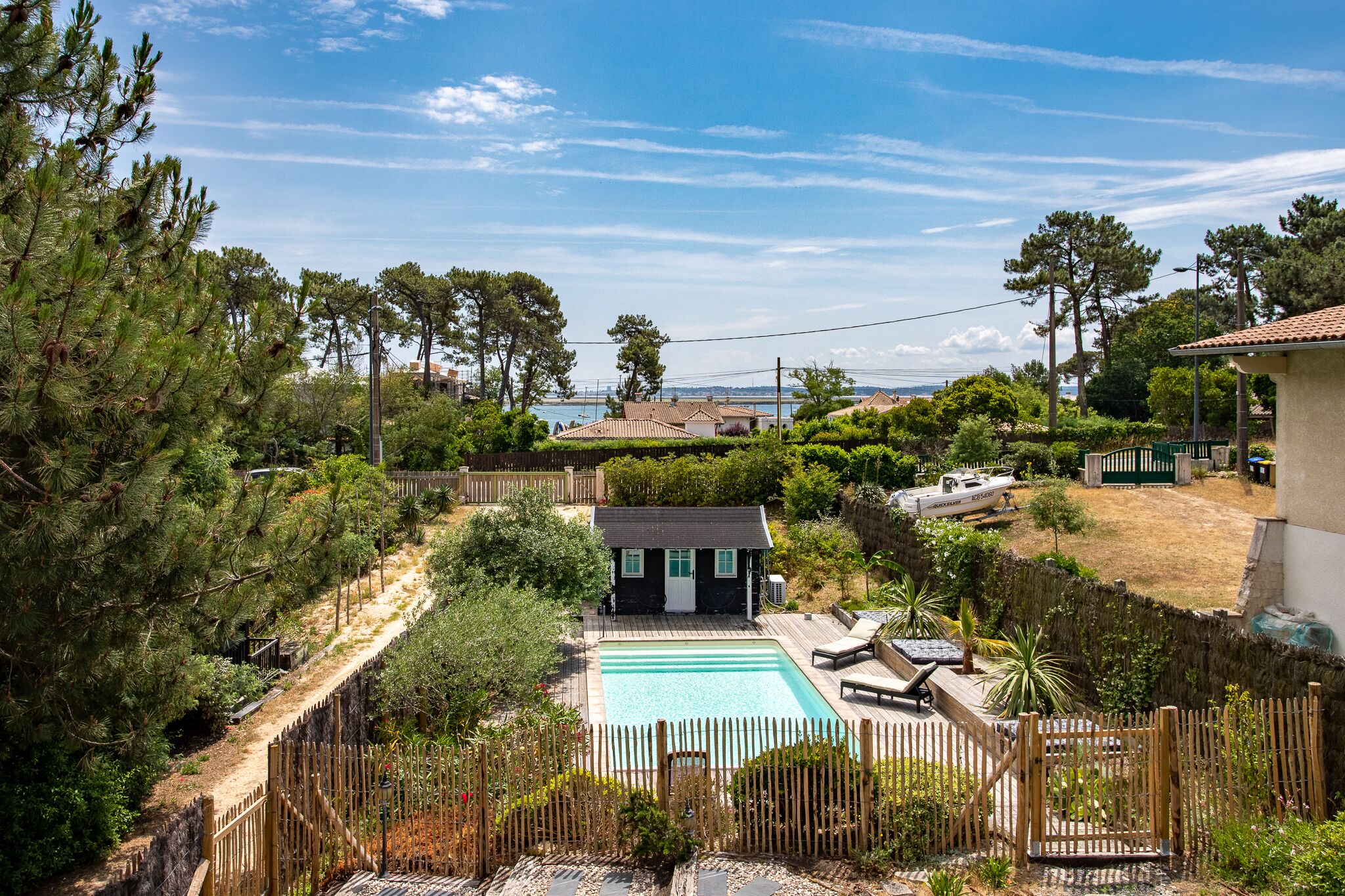 A residential property with a swimming pool, wooden deck, and a view of the sea.