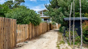 A two-story house with a balcony, surrounded by a wooden fence and trees. - Villa des Sables pool, 100M from the beach (Lège-Cap-Ferret)