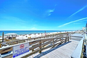 A beach view with a wooden boardwalk and a sign prohibiting pets.