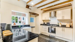 Una cocina con isla central, estufa y ventana con vista a zonas verdes.