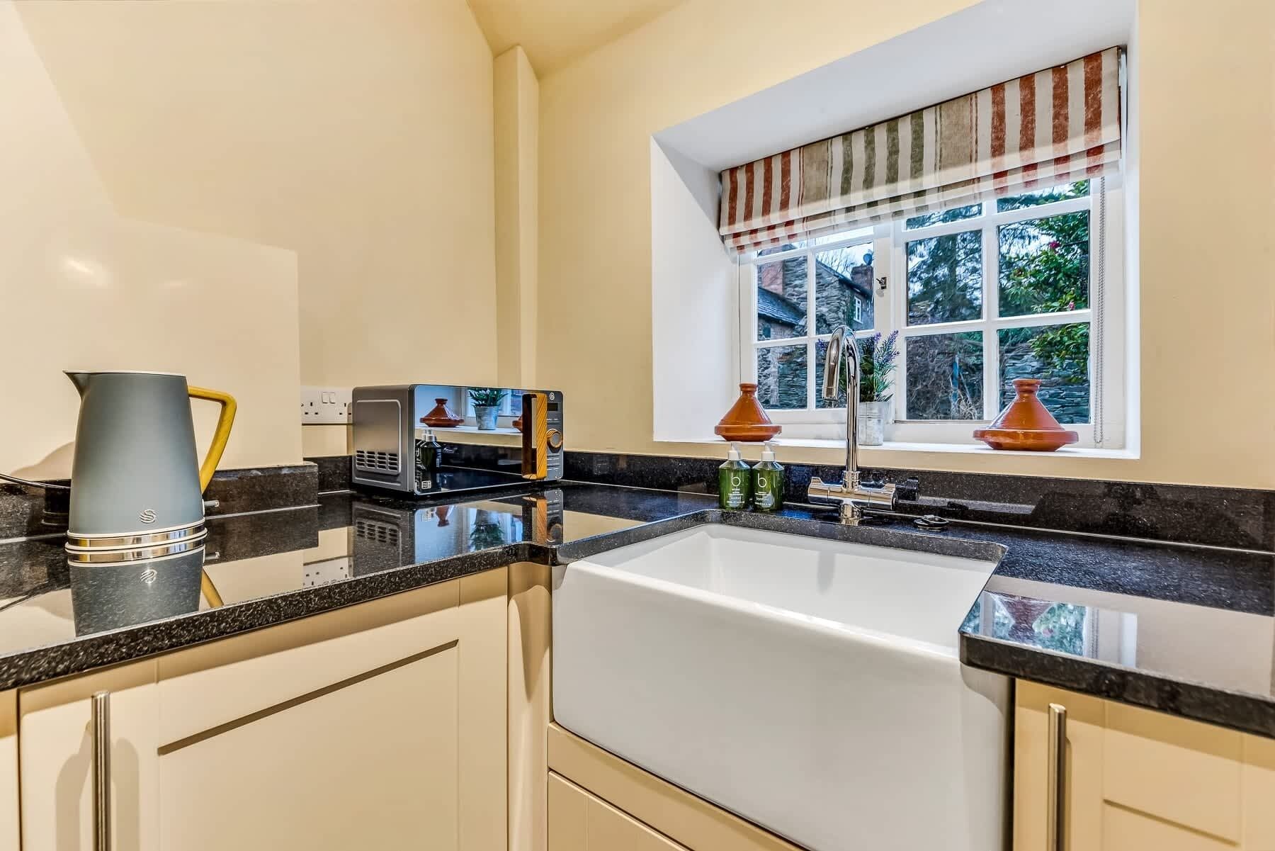 A kitchen with a sink, a microwave, and a kettle.
