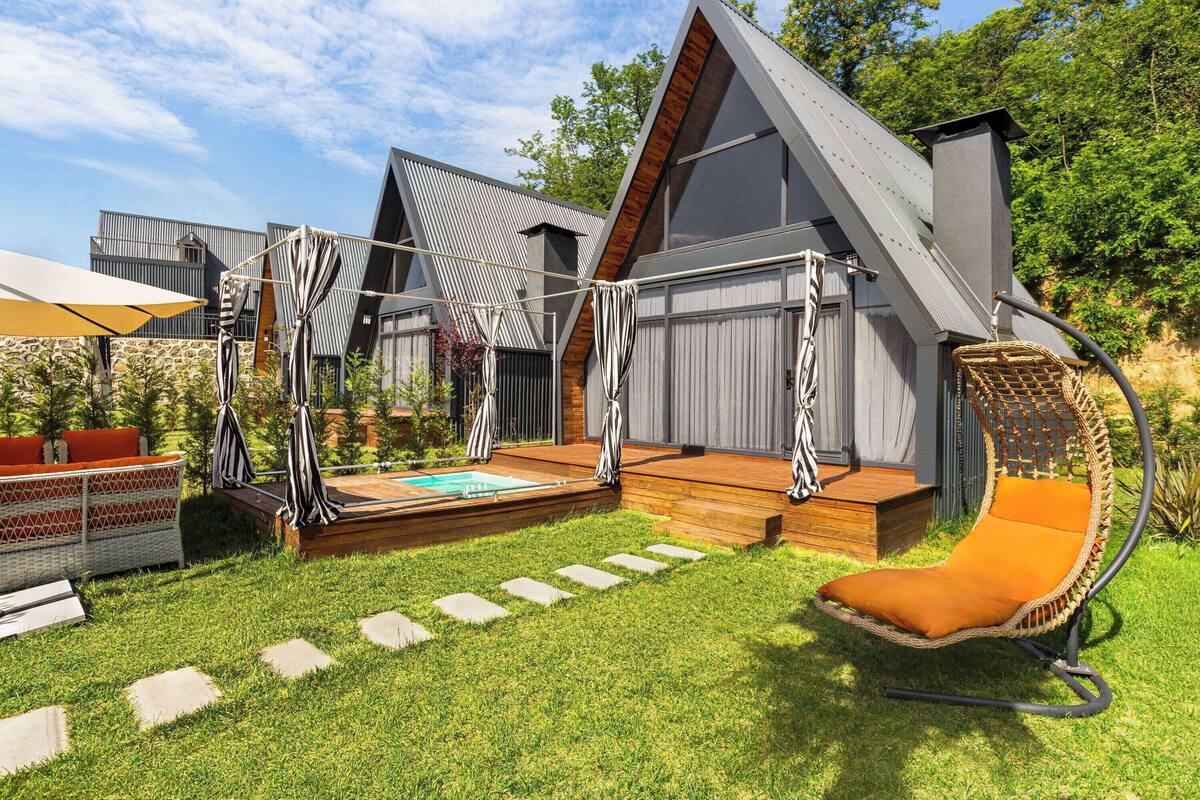 A modern outdoor area with a pool, wooden deck, and a hanging chair.