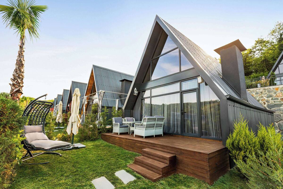A modern house with a sloped roof, large windows, and a wooden deck.
