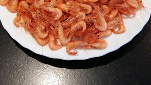 A white plate filled with cooked shrimp on a dark surface. - Maison Bord de mer Avec Jardin Clos (Ploudalmézeau)