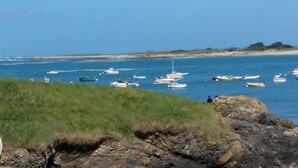A coastal view with boats on the water and rocky terrain in the foreground. - Maison Bord de mer Avec Jardin Clos (Ploudalmézeau)
