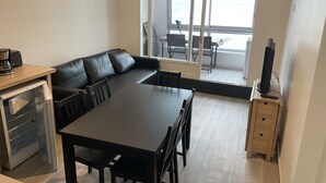A compact living space with a dining table, a sofa, a coffee maker, and a TV on a stand. - Petit Cocon Courseullais with 2-star sea view (Courseulles-sur-Mer)