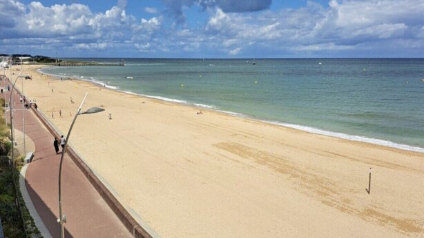 A beach with a paved walkway and a pier in the background. - Petit Cocon Courseullais with 2-star sea view (Courseulles-sur-Mer)