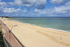 Une plage avec une promenade dallée et une jetée en arrière-plan.