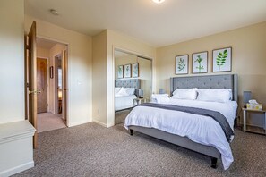 Une chambre à coucher avec un grand lit, une table de chevet, une commode et un miroir.