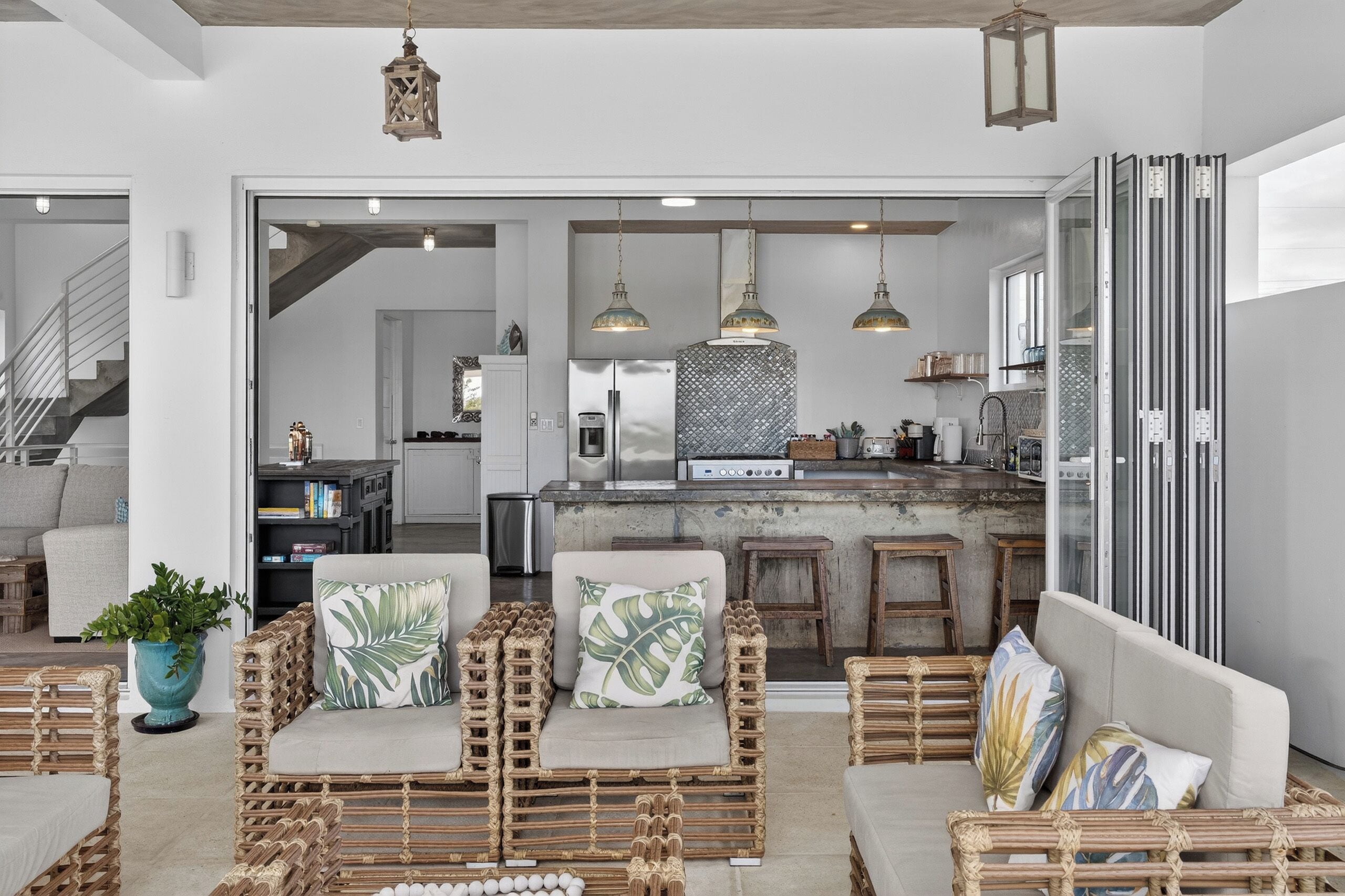 Een moderne keuken met een centraal eiland, hanglampen en uitzicht op de woonkamer.