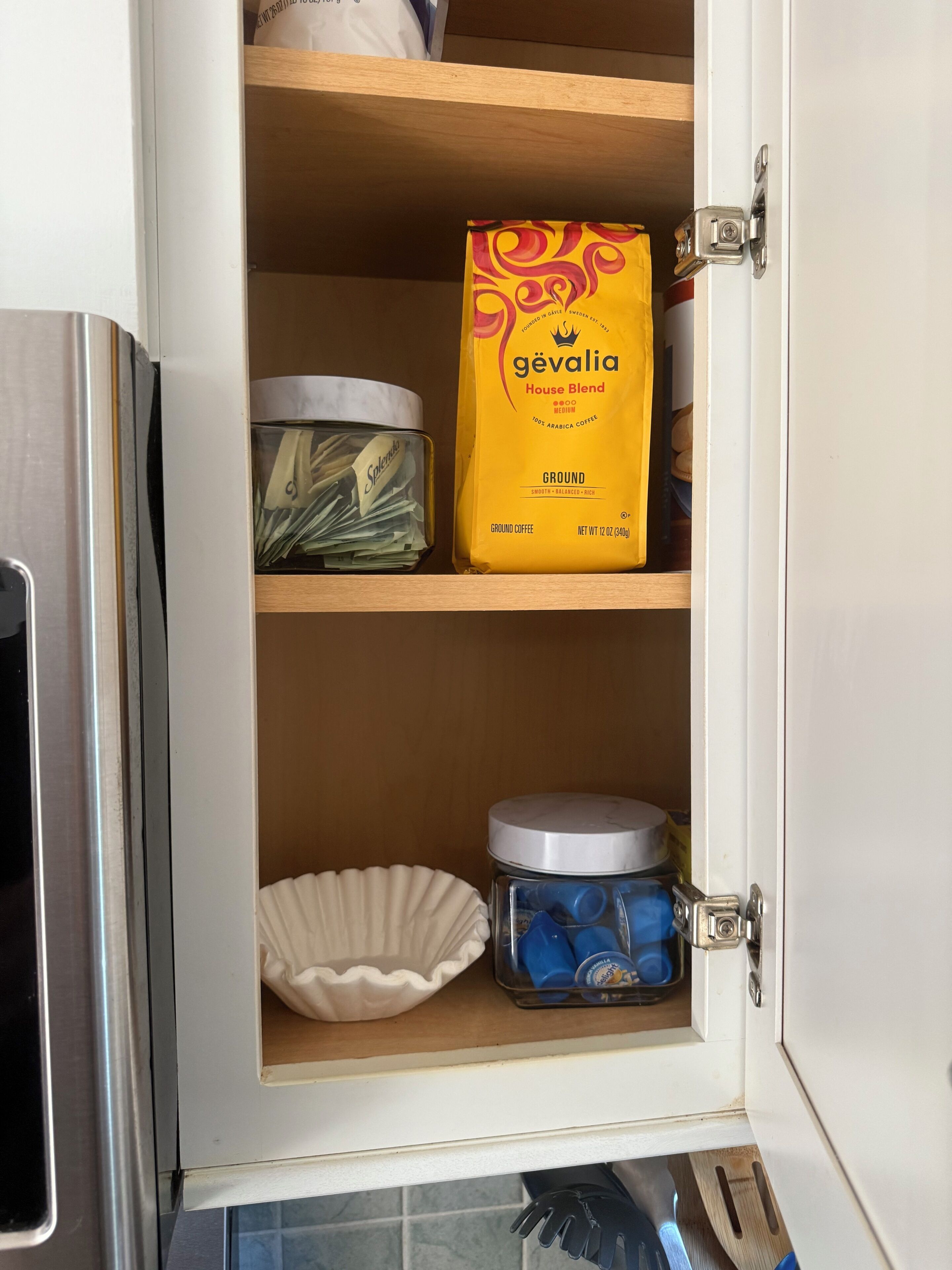 Un mueble de cocina con un paquete de café, un tarro de granos de café y un plato.