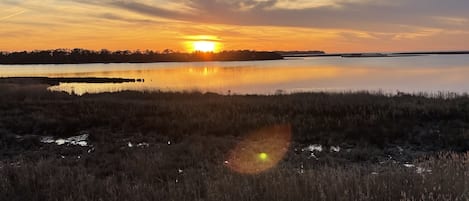 A sunset over a calm lake with a wooden deck in the foreground.