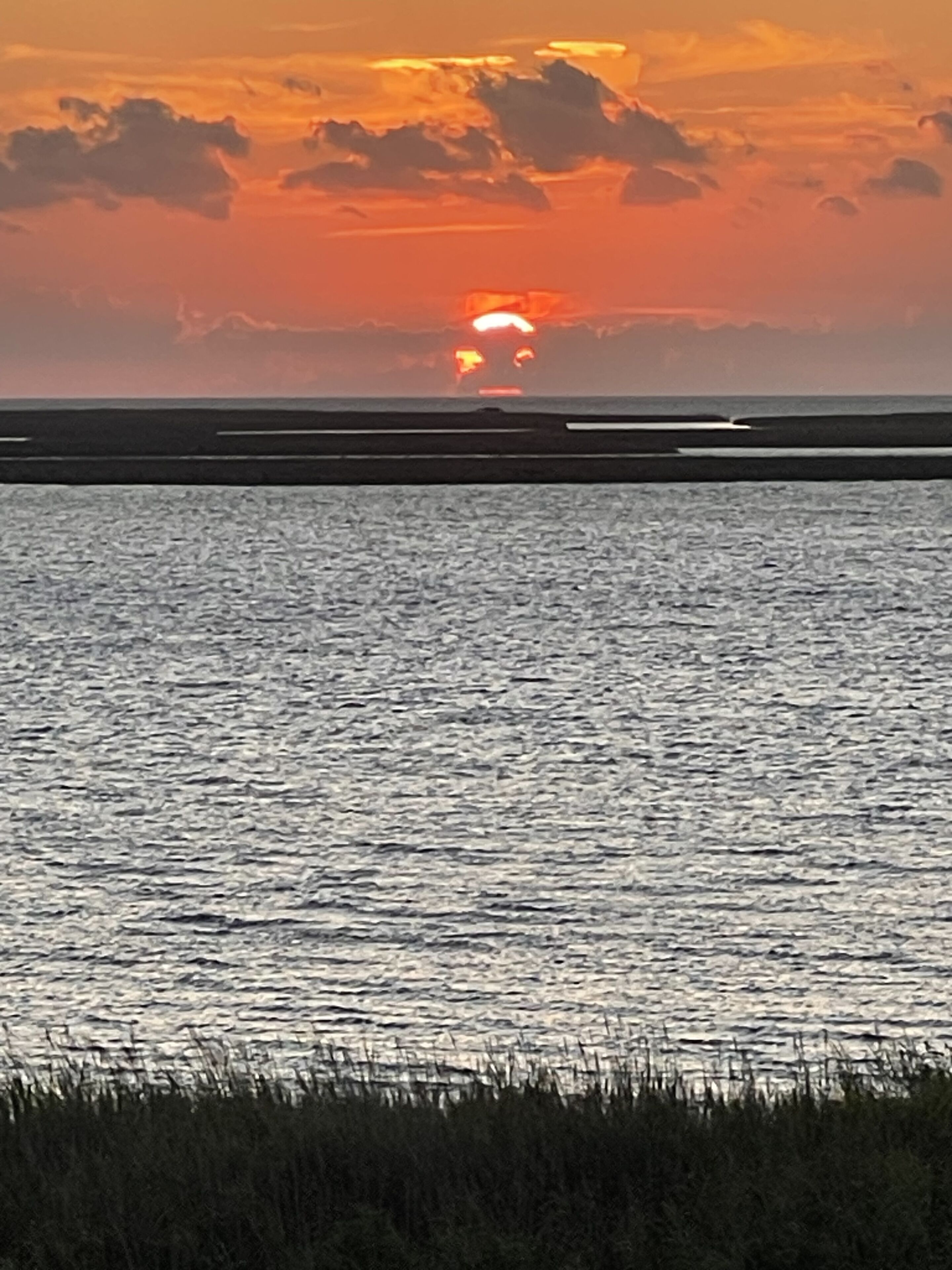 Ein Sonnenuntergang über ruhigem Wasser, der Horizont in der Ferne.