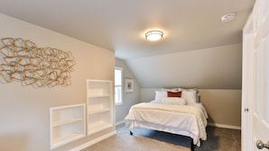 A bedroom with a bed, a white wall art piece, built-in shelves, and a ceiling light. - Christmas City Cottage (Bethlehem)