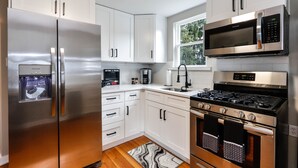 A modern kitchen with stainless steel appliances, white cabinetry, and a built-in oven. - Christmas City Cottage (Bethlehem)