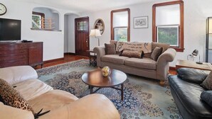 Una sala de estar con un sofá, una mesa de centro, un televisor y un mueble de madera.