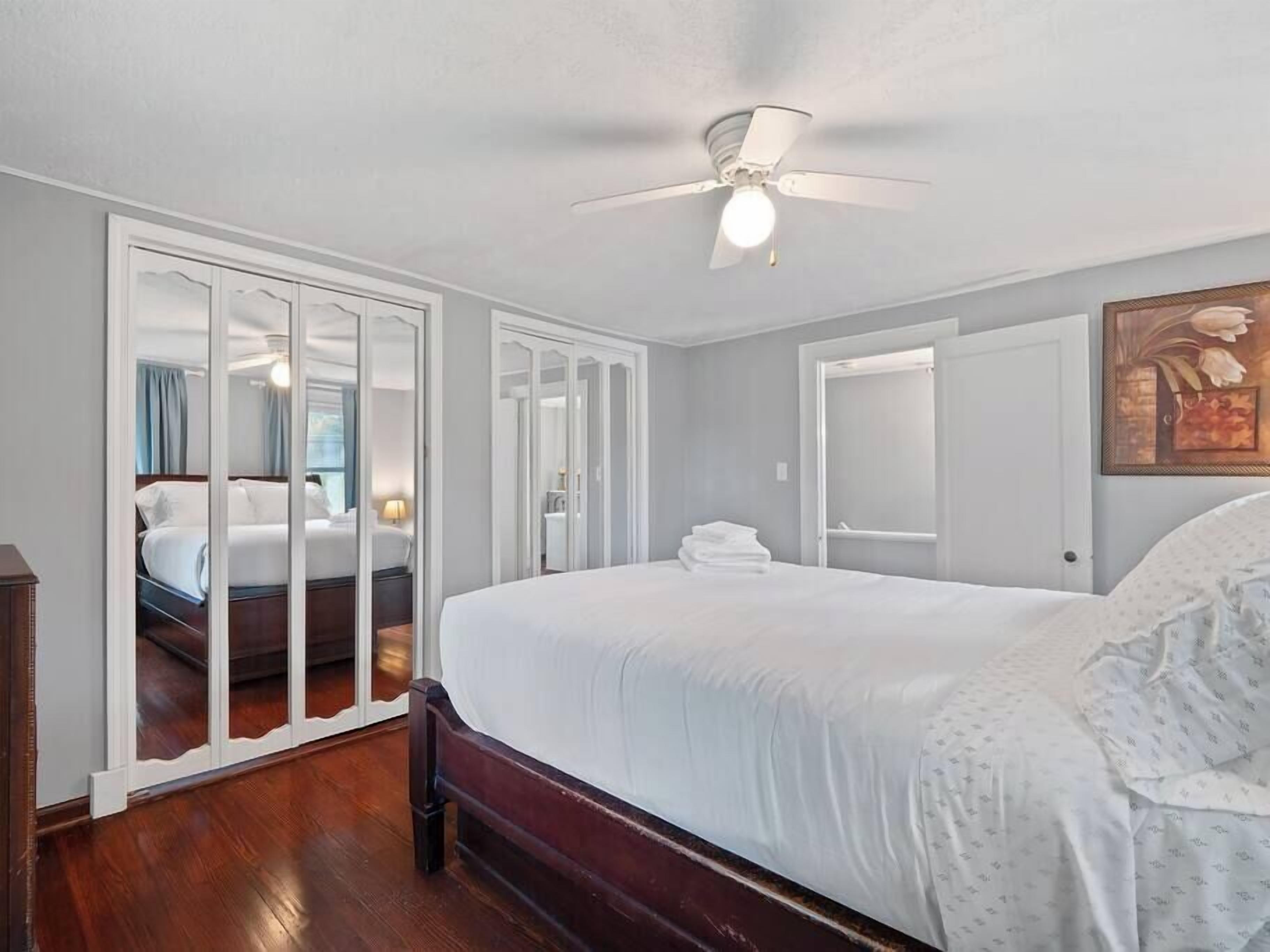 Une chambre d’hôtel avec un grand lit, un ventilateur de plafond et une armoire avec un miroir.