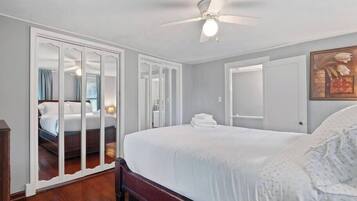 Une chambre d’hôtel avec un grand lit, un ventilateur de plafond et une armoire avec un miroir.