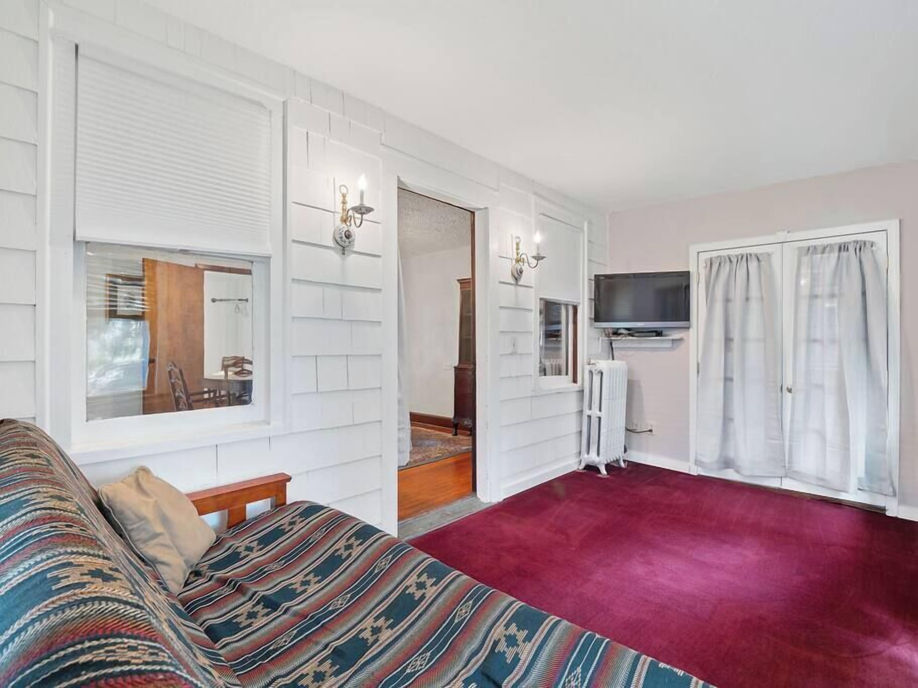 Een kamer met een bed, een televisie, een spiegel en een raam.