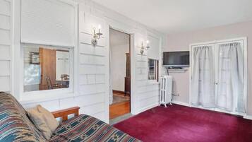 Een kamer met een bed, een televisie, een spiegel en een raam.