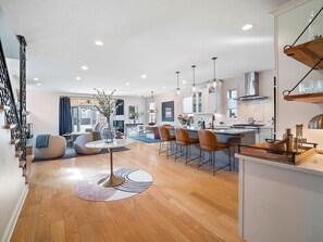 A modern kitchen with a central island, pendant lights, and a dining area with bar stools.