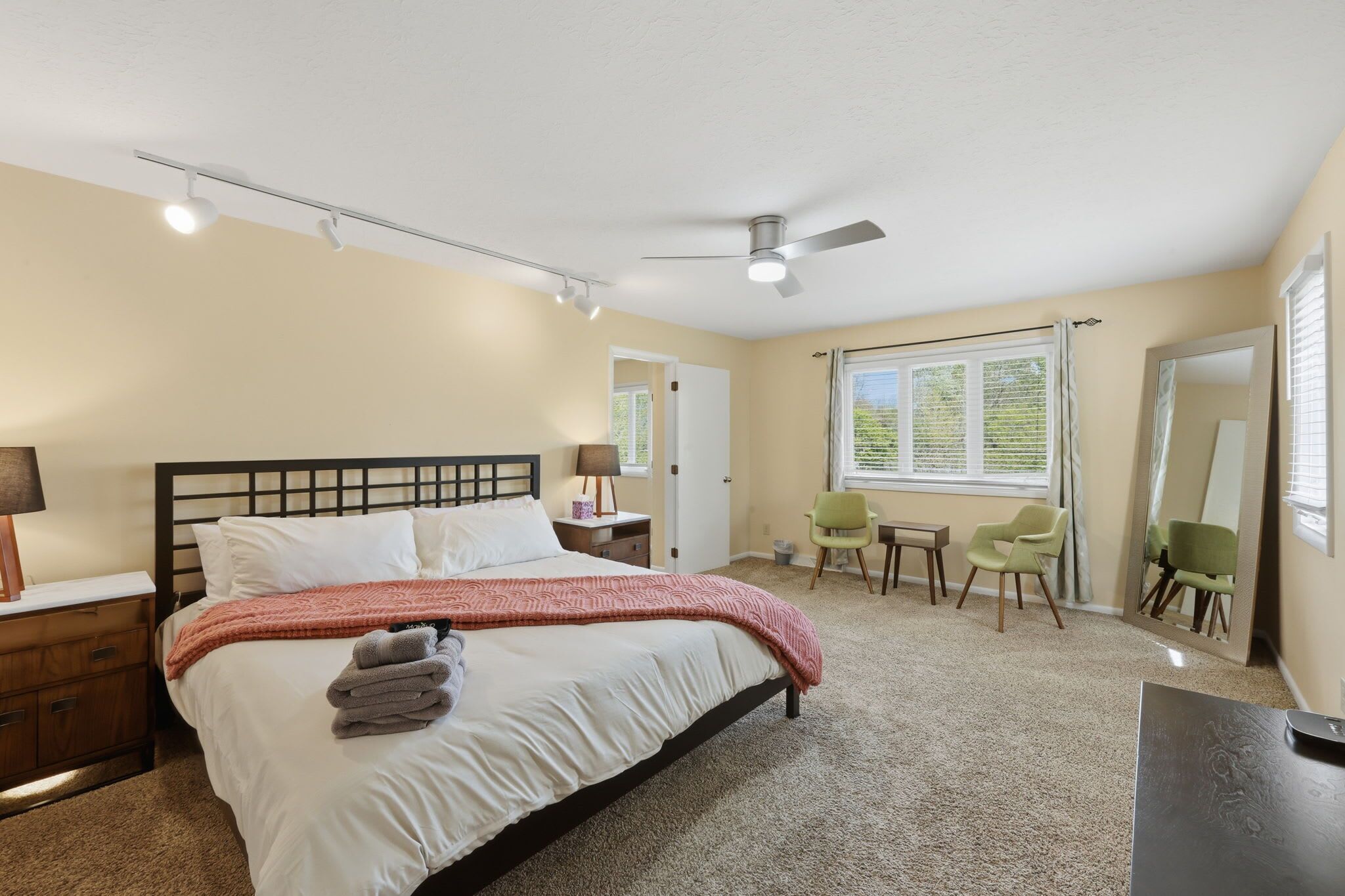 Une chambre à coucher comprenant un lit, une table de chevet, une lampe, une chaise et un ventilateur de plafond.