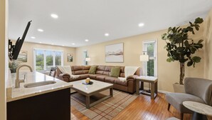 A living room with a sofa, coffee table, and a plant. - 5 King Beds, Hot Tub, Sleeps 10 - Pet Friendly & Close to Clinic (Pepper Pike)