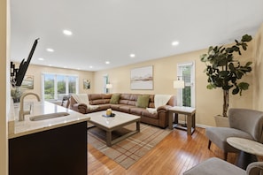A living room with a sofa, coffee table, and a plant. - 5 King Beds, Hot Tub, Sleeps 10 - Pet Friendly & Close to Clinic (Pepper Pike)