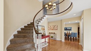 A spiral staircase with wooden steps and white railings, leading to a dining area with a table and chairs. - 5 King Beds, Hot Tub, Sleeps 10 - Pet Friendly & Close to Clinic (Pepper Pike)