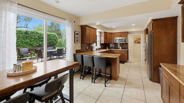 A modern kitchen with a large island, wooden cabinets, and a dining area with a table and chairs. - 5 King Beds, Hot Tub, Sleeps 10 - Pet Friendly & Close to Clinic (Pepper Pike)