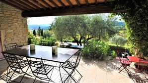 Eine Terrasse im Freien mit einer Steinmauer, einer Holzpergola und einem Tisch mit Stühlen.