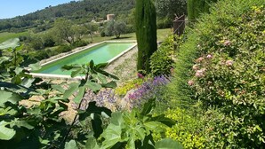Ein rechteckiger Pool, umgeben von üppigem Grün und blühenden Pflanzen.
