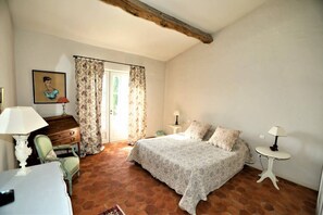 Ein Schlafzimmer mit einem Bett, zwei Nachttischen, einem Sessel, einem Schreibtisch und einem Bild an der Wand.