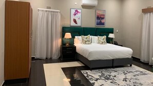 A modern bedroom with a large bed, a nightstand, an air conditioning unit, and a wardrobe. - Topaz Villas (Lilongwe)