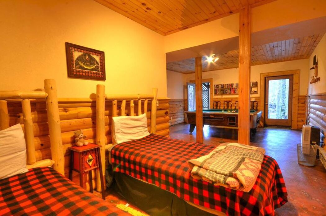 Una habitación tipo cabaña de madera con dos camas, techo de madera y vistas al exterior.