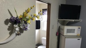 Ein kleines Badezimmer mit Toilette, einem weißen Waschbecken, einem weißen Kühlschrank und einer Mikrowelle darauf.