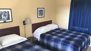 Ein Hotelzimmer mit zwei Betten, einem Nachttisch, einer Lampe und zwei gerahmten Bildern an der Wand.