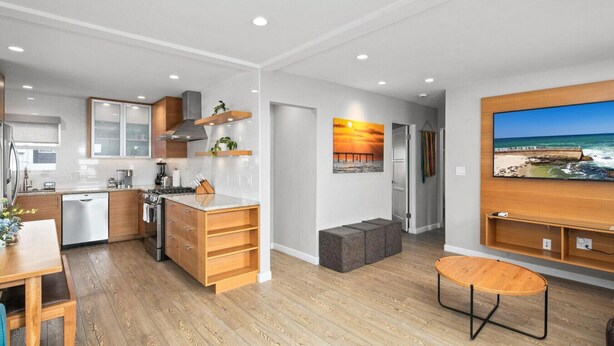 A modern kitchen with wooden cabinets, a built-in oven, and a dining area with a wooden table and bench. - 7BD Family, Event Friendly 5min 2 Beach, Boardwalk (San Diego)