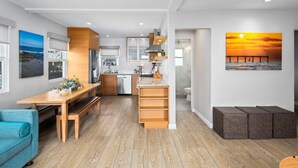 A modern kitchen with wooden cabinets, a dining area with a bench, and a view of the sunset through a window. - 7BD Family, Event Friendly 5min 2 Beach, Boardwalk (San Diego)