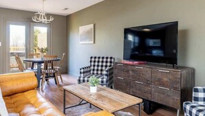 A living room with a sofa, a coffee table, a TV, and a dining area with chairs and a table.